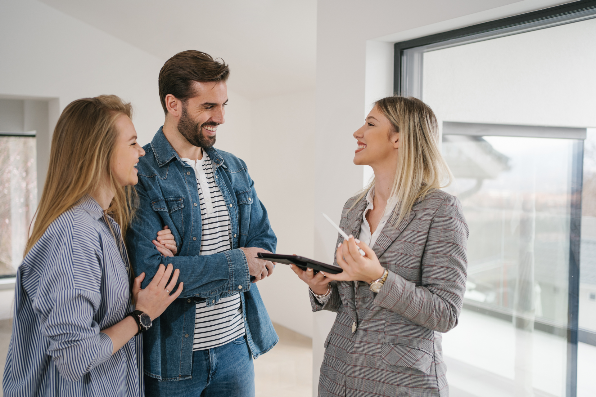 Three people talk in a bright office, one holding documents and smiling.