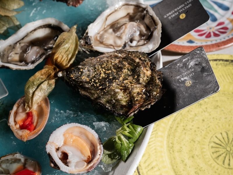 Ostriche e frutti di mare assortiti su ghiaccio con limone e guarnizione, disposti su un piatto scuro