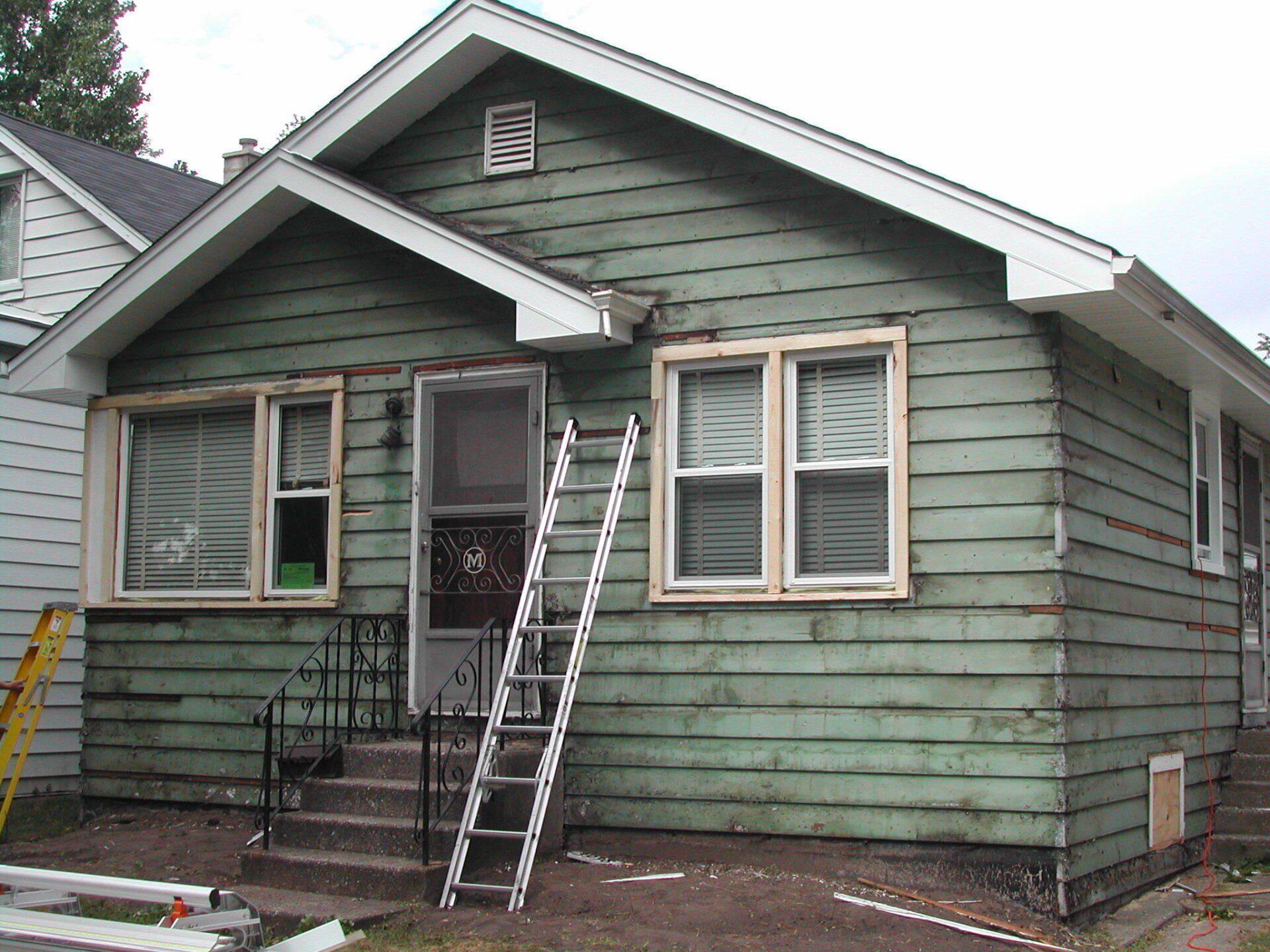 A green house with a ladder in front of it
