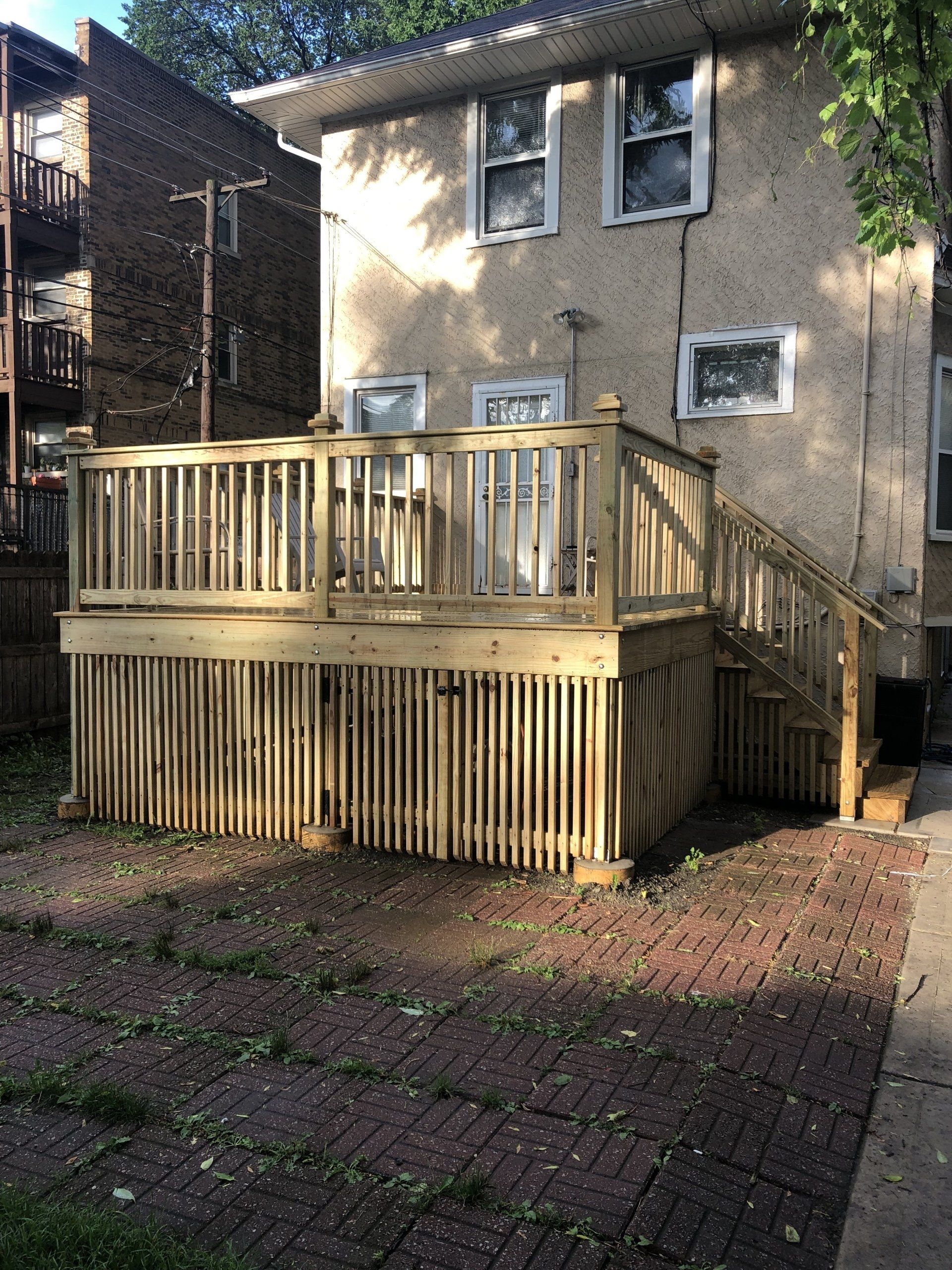 A wooden deck with stairs is in front of a house.