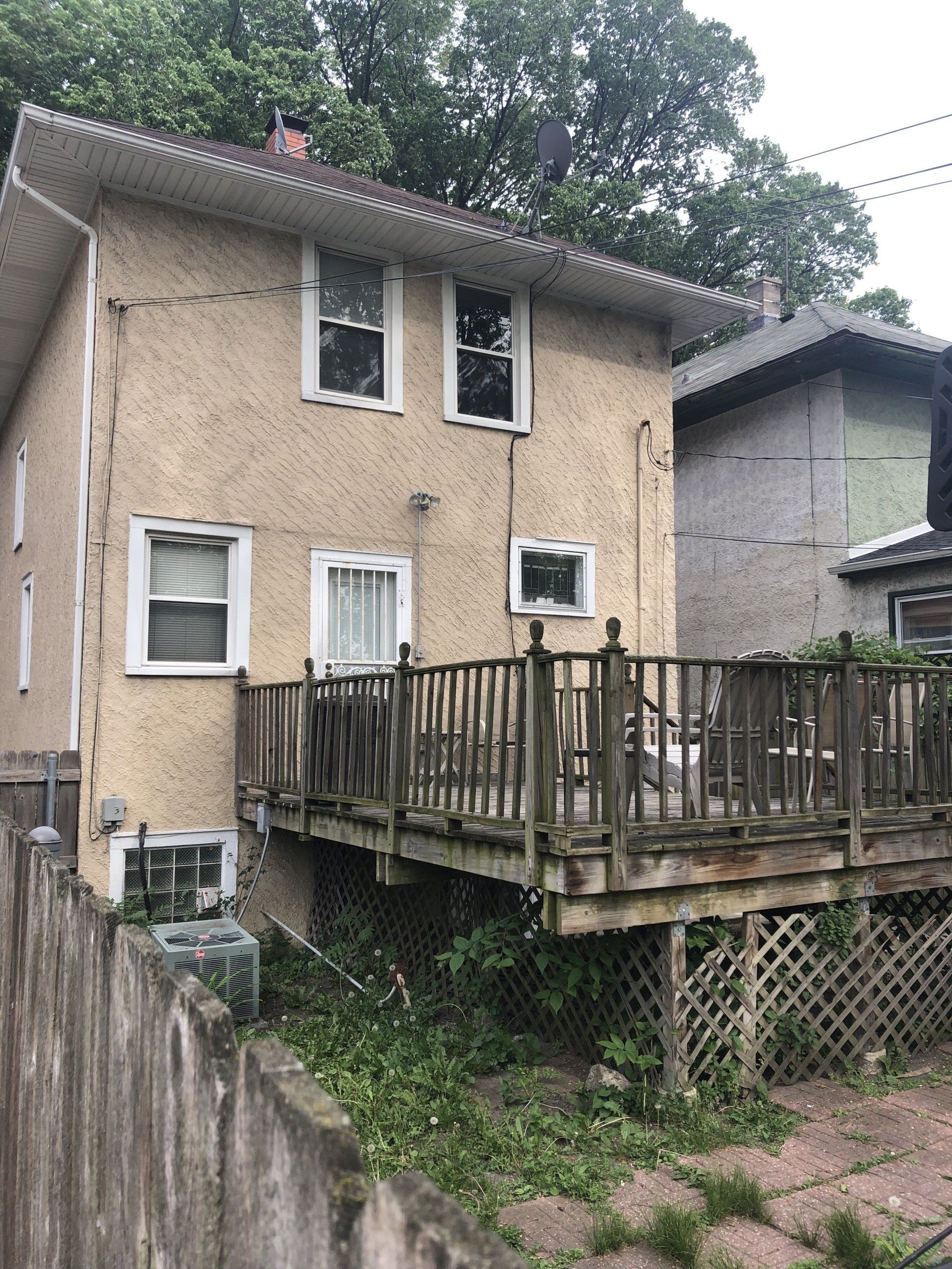 A house with a deck and a fence in front of it.
