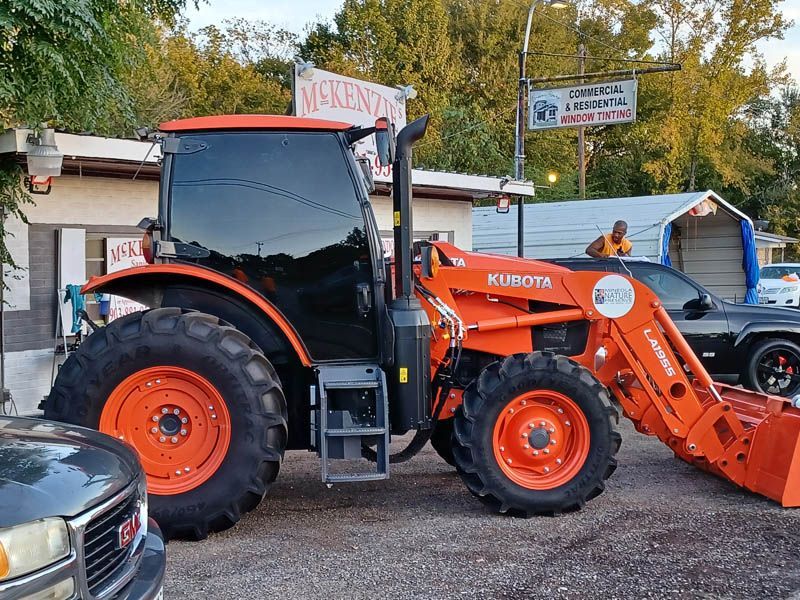 Orange Kubota tractor with front loader parked outside a building.