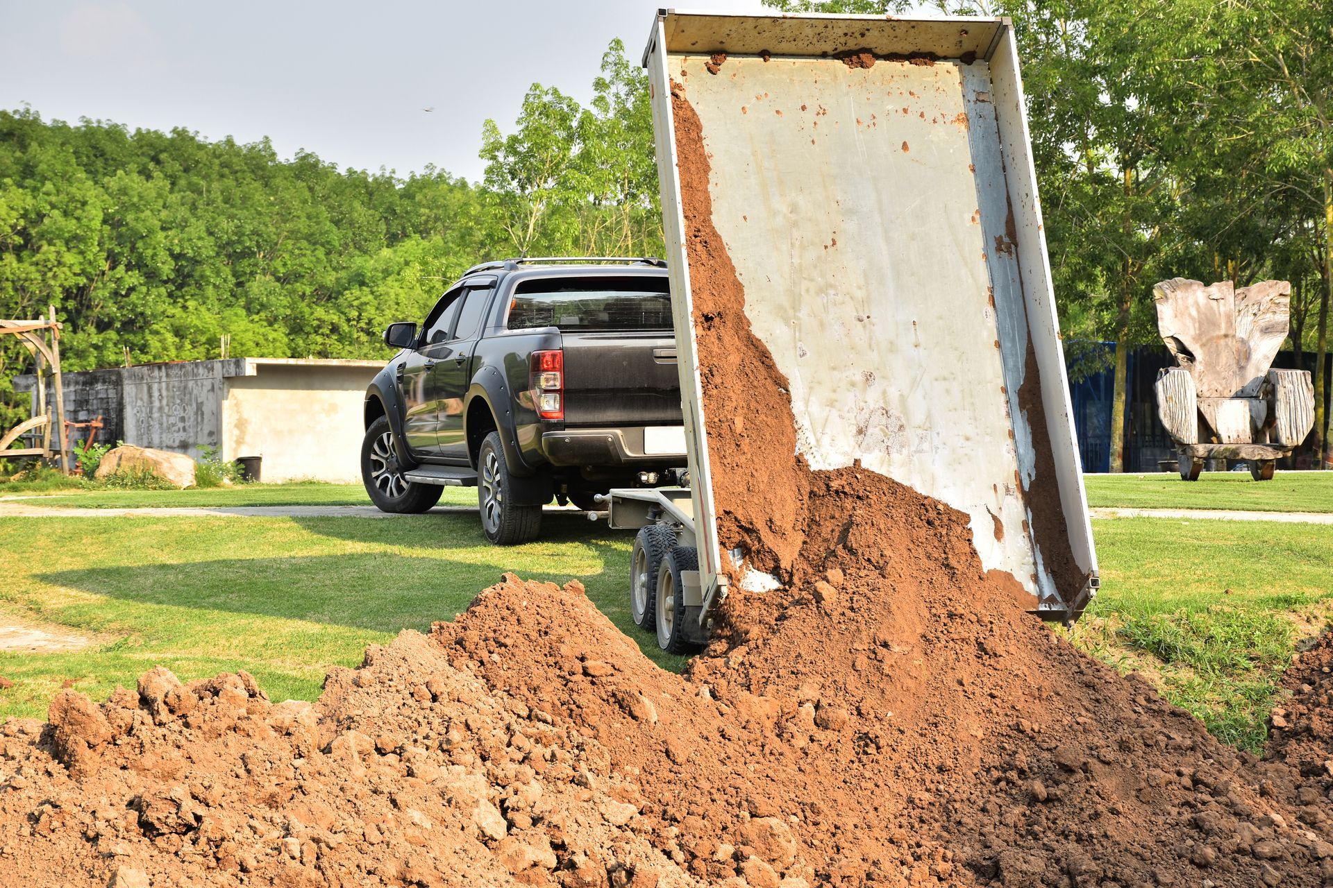Black dump trailer on grass with a green