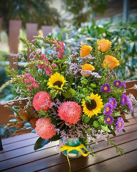 A Vase Filled with Flowers Is Sitting on A Wooden Table — Ivy Lane Flowers & Gifts in Birtinya, QLD