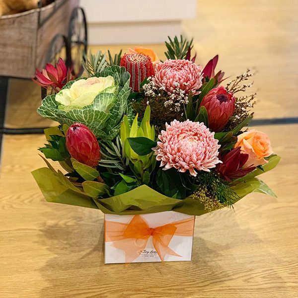 A Box Filled with Flowers and Leaves on A Wooden Table — Ivy Lane Flowers & Gifts in Birtinya, QLD