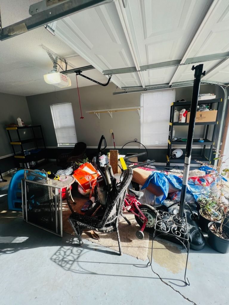 A cluttered garage with a black metal chair, a folded red bicycle, various storage racks, and miscellaneous items.