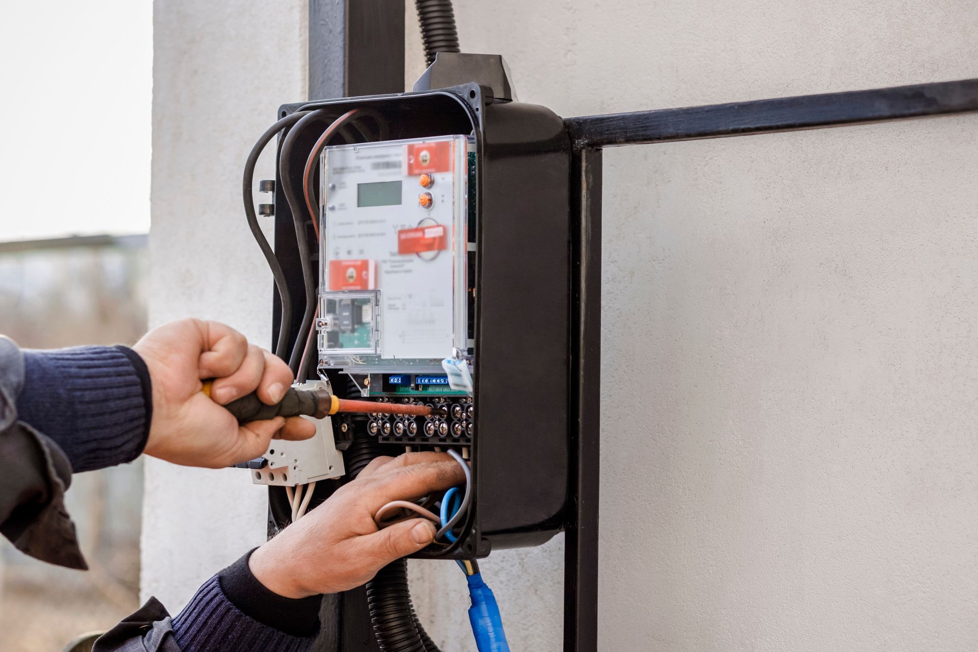 Technician wiring an electrical control panel mounted on a wall.