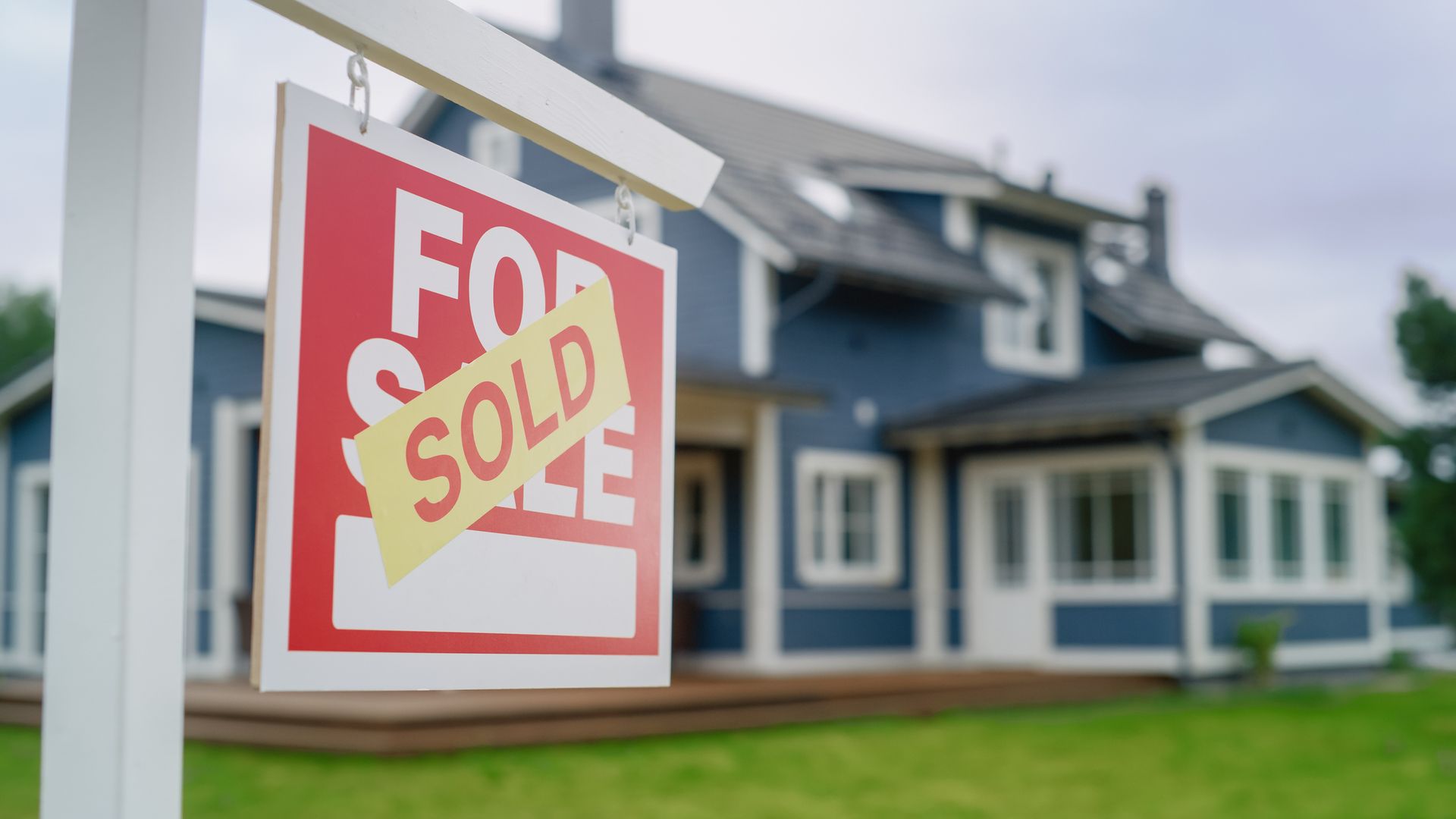 A for Sale Sign Is Hanging in Front of A Blue House – Dayton, OH – Home Services Title