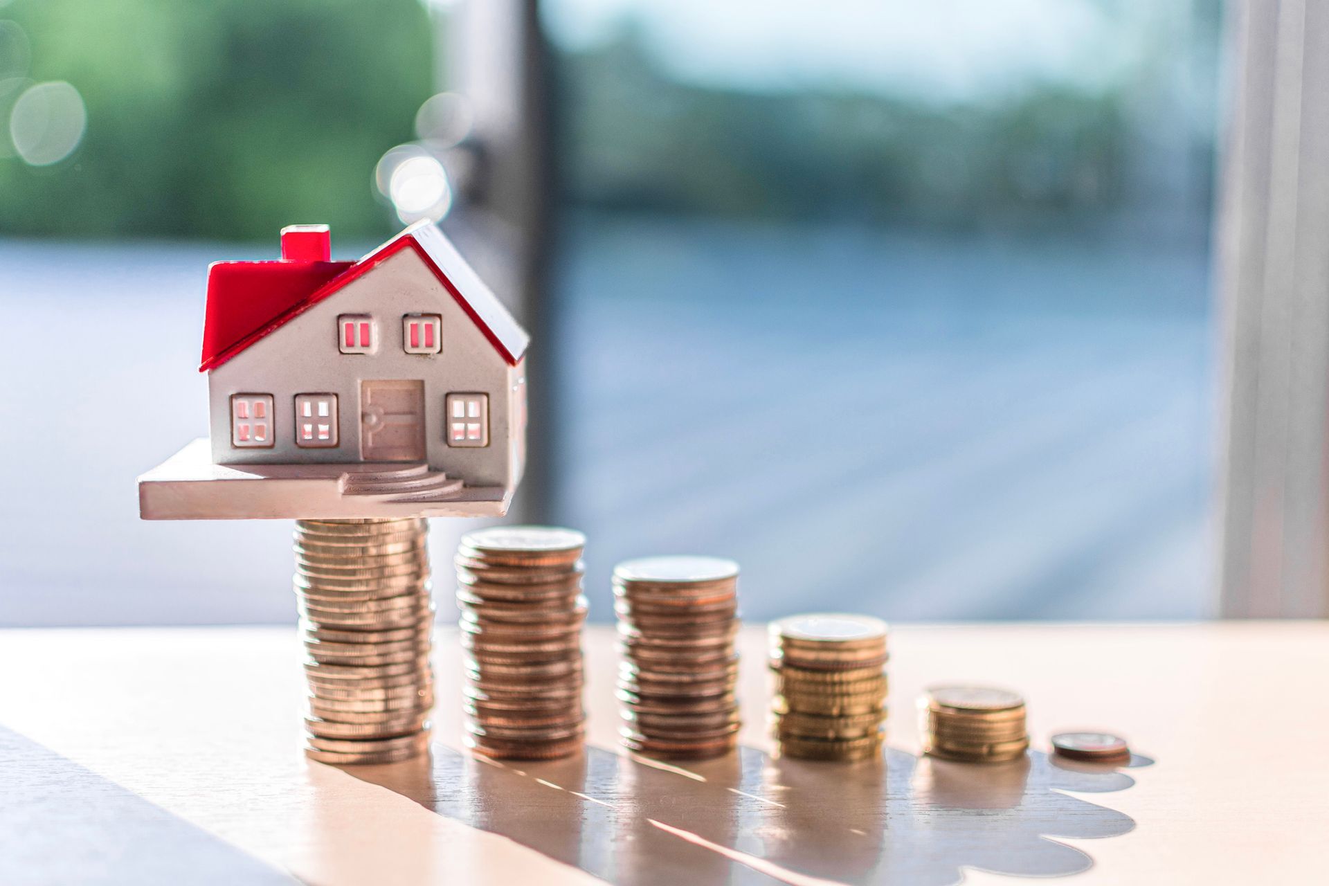 A Model House Is Sitting on Top of Stacks of Coins on A Table – Dayton, OH – Home Services Title