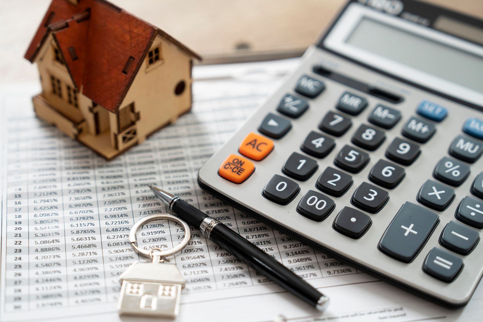 A Calculator , Pen , Keychain and Model House Are on A Table – Dayton, OH – Home Services Title