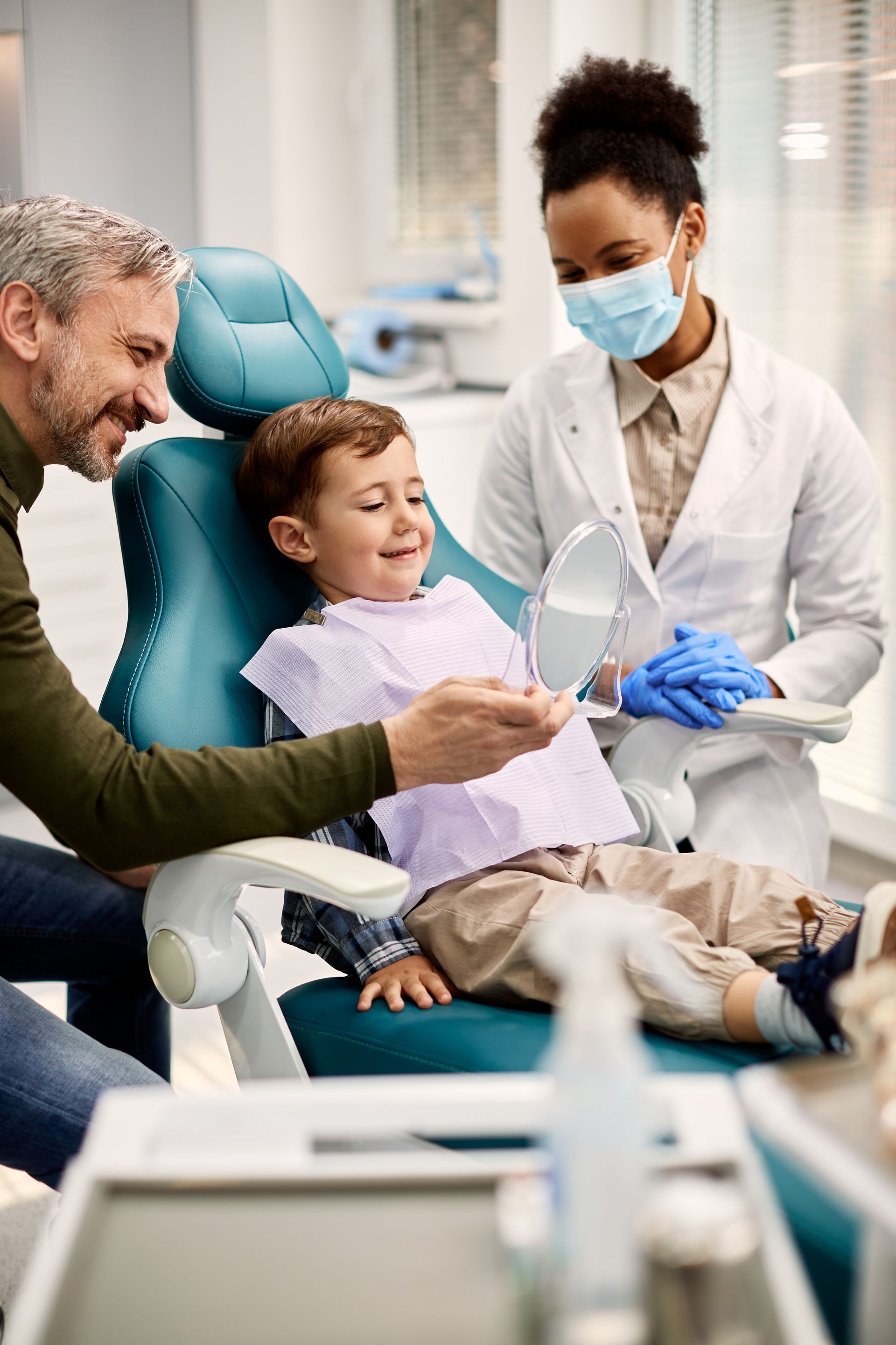 Trust our family dentist for your kids in Somerset, NJ. Kid smiling in mirror in dentist chair | Dentist for kids in Somerset, NJ
