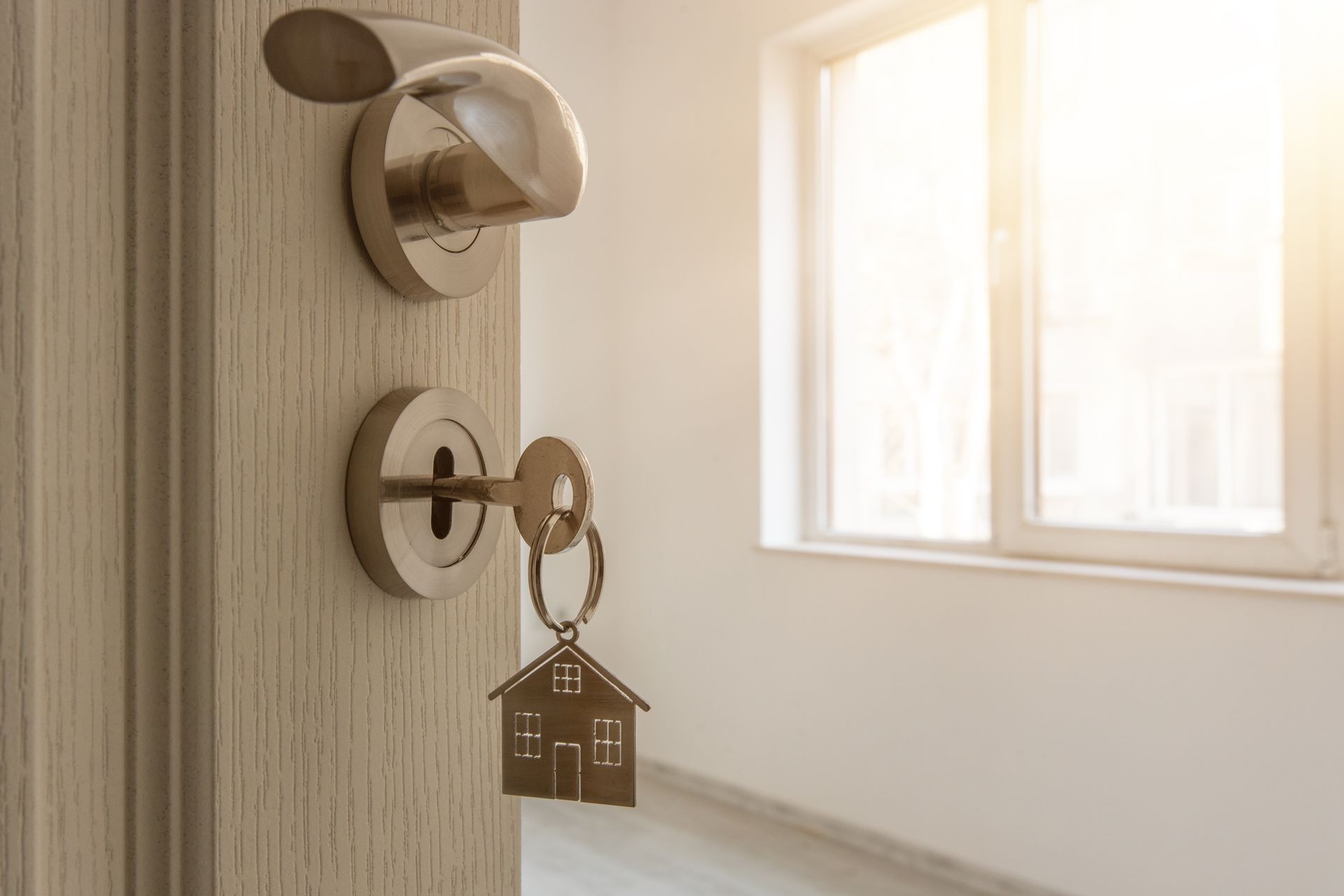 A door with a key in it and a keychain in the shape of a house.