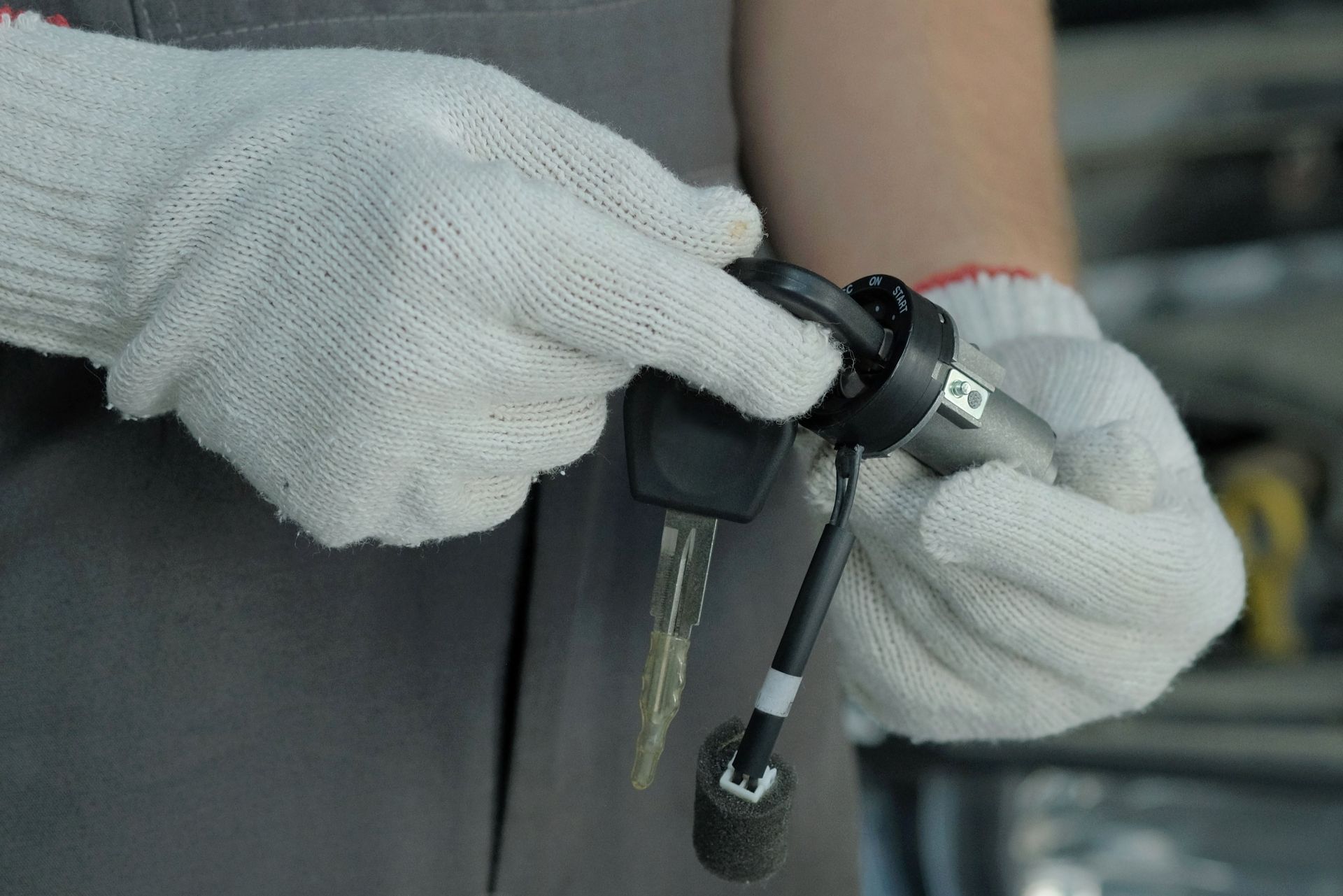 A person wearing white gloves is holding a car key.