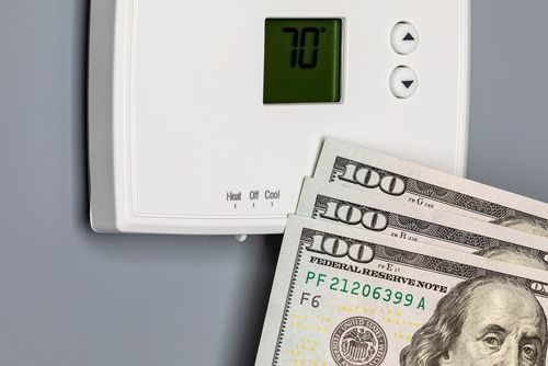 Technician performing a furnace tune-up on thermostat saving the customer money