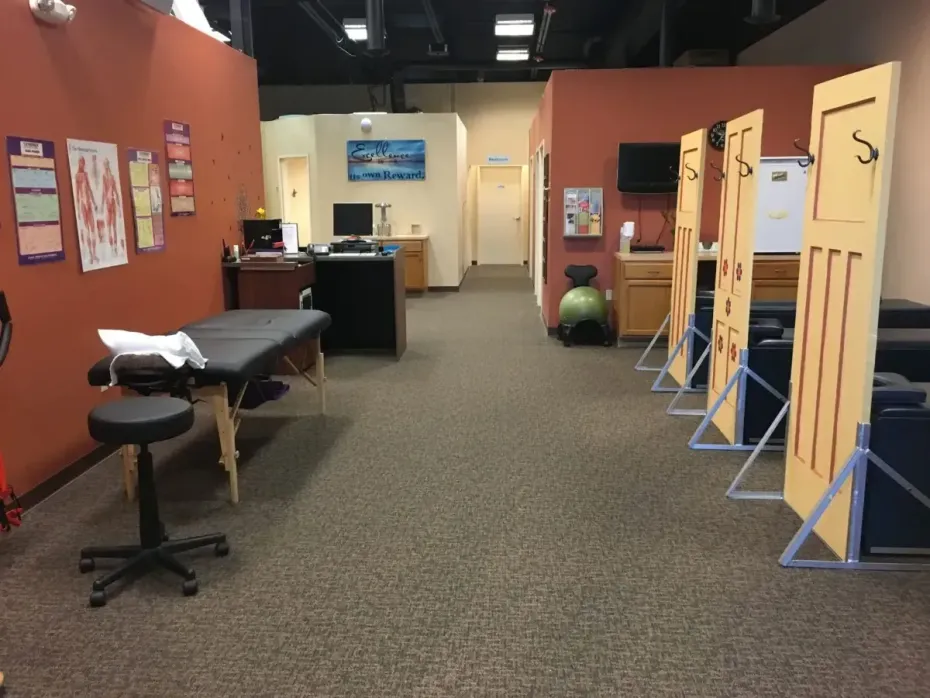 Empty clinic hallway with exam tables, privacy screens, and bulletin boards