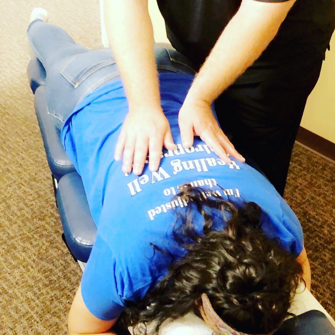 Person receiving a back massage on a treatment table, wearing a blue shirt.