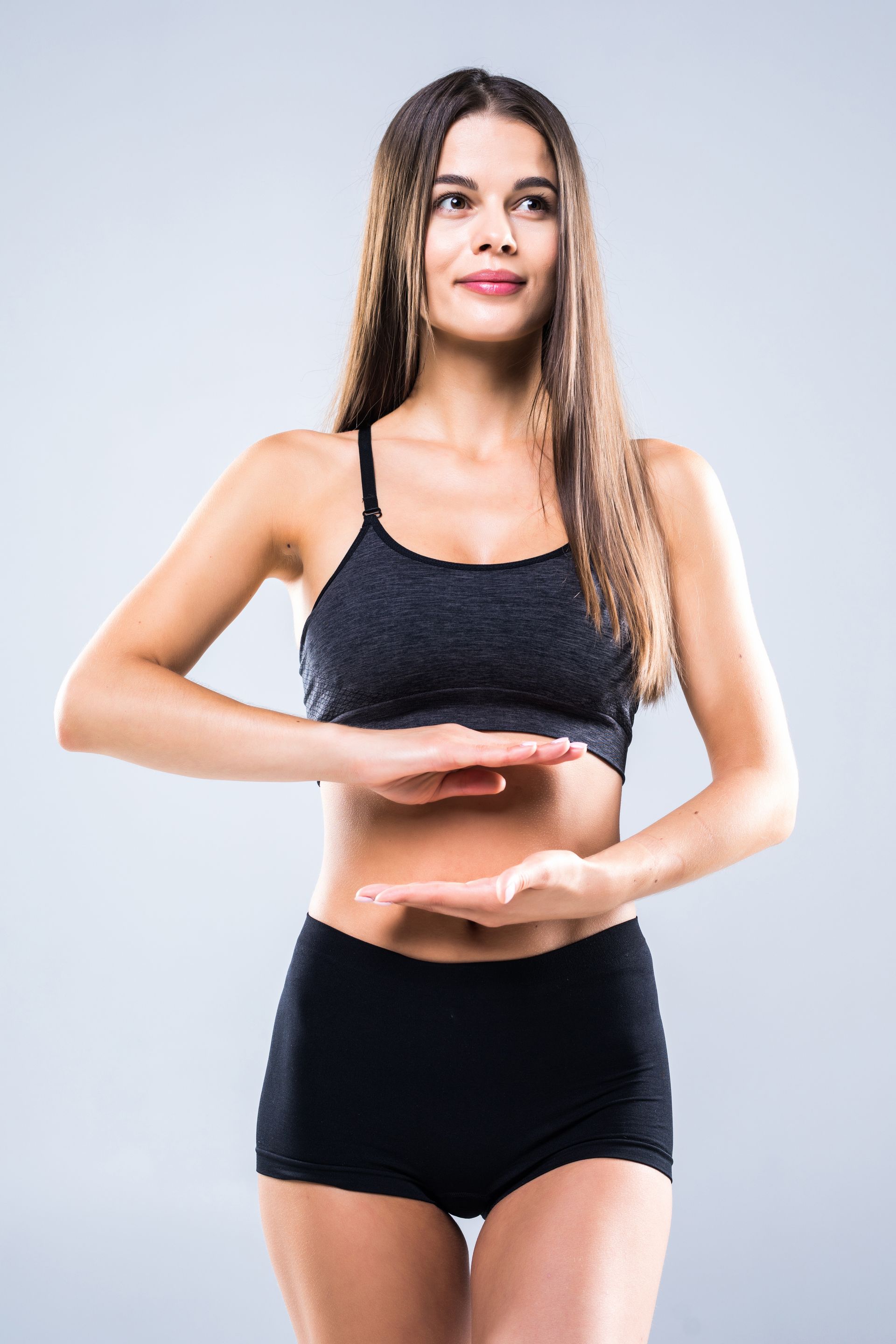 Woman in black workout clothes holding a yoga pose against a light gray background