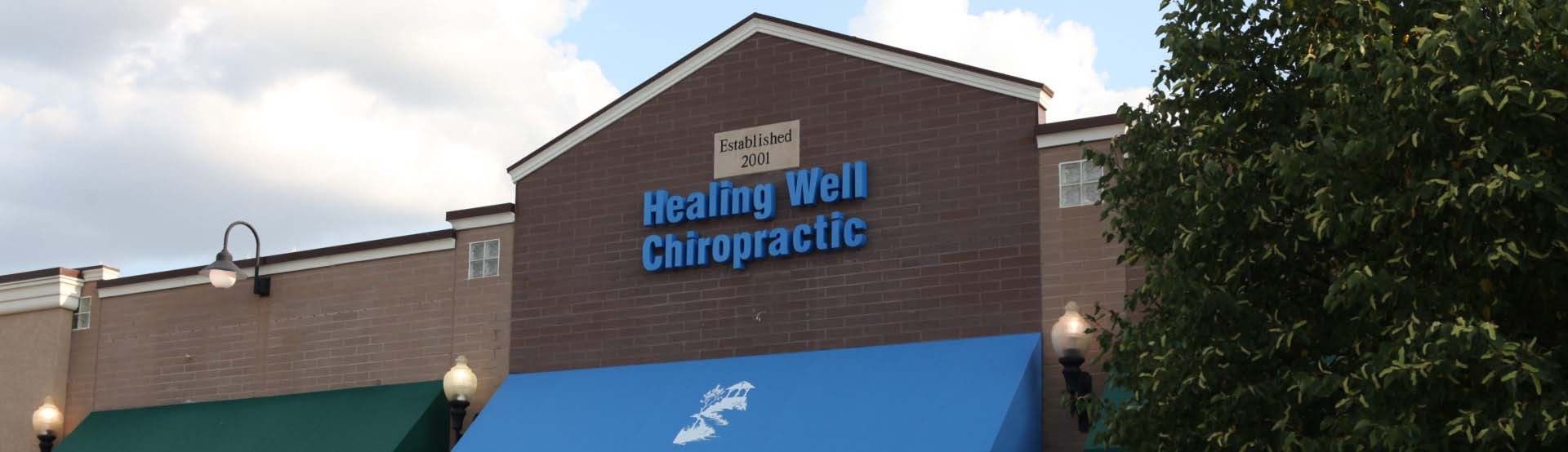 Health Well Chiropractic storefront with blue awning and brick facade