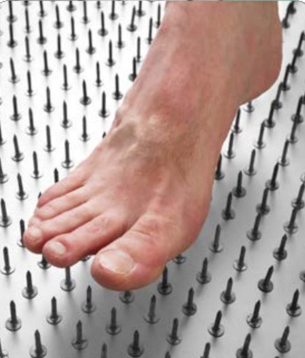 Bare foot stepping on a bed of metal acupuncture-style spikes