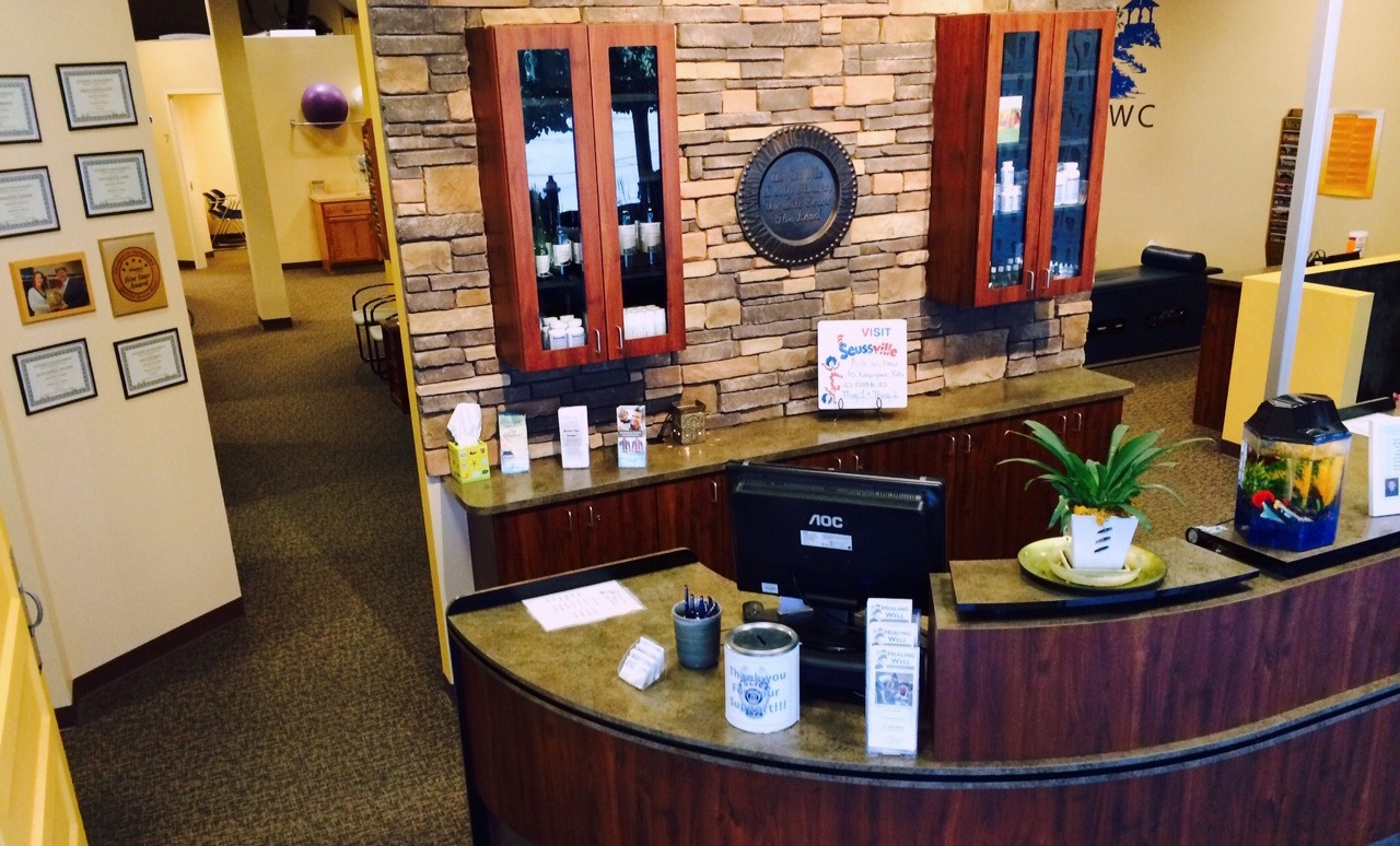 Office lobby reception desk with brick accent wall, wood counter, and potted plants