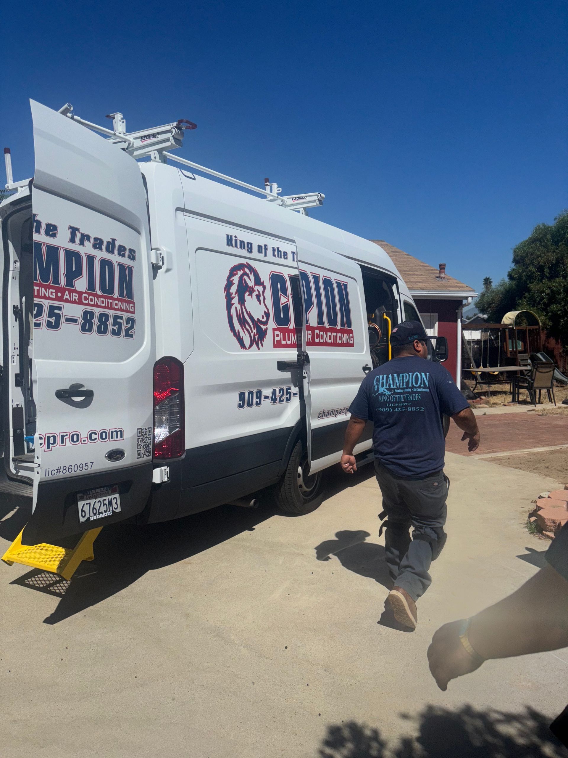 Man exiting a white work van with company logo and text. Sunny outdoors.