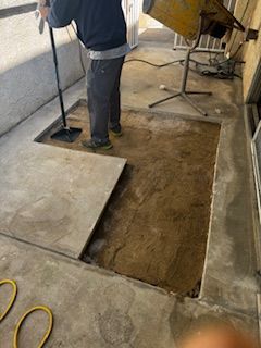 A man is cleaning a hole in the ground with a vacuum cleaner.