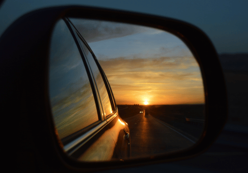 Sunset reflected in a car side mirror on an open road