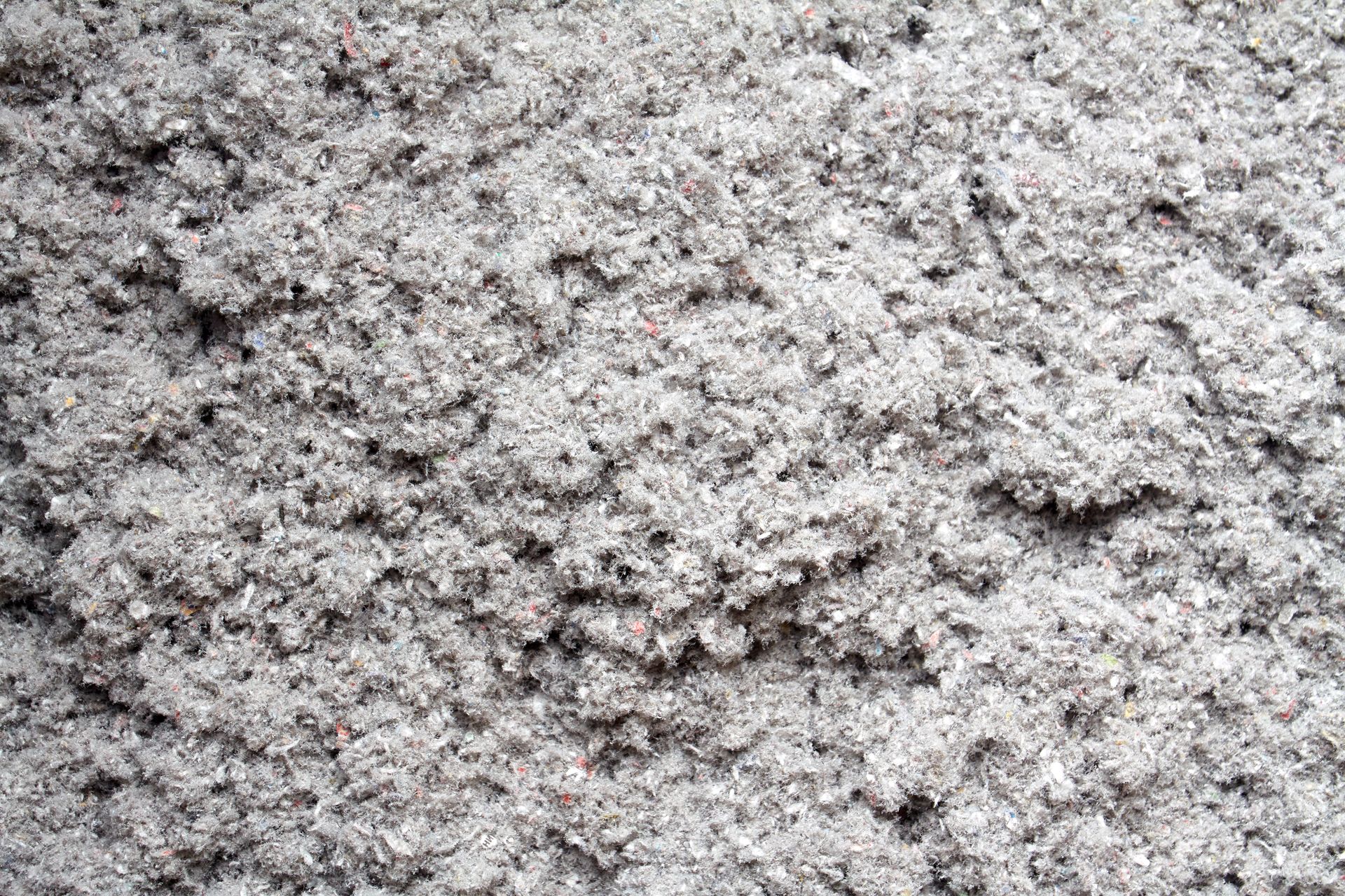 Gros plan d'un matériau gris texturé, ressemblant à du sable ou à des particules finement broyées.
