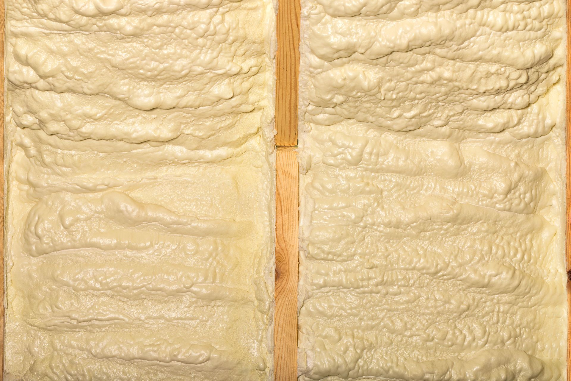 Deux montants en bois avec de la mousse isolante jaune remplissant les espaces entre eux.