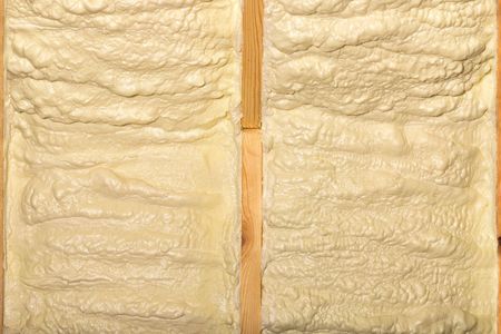 Deux montants en bois avec de la mousse isolante jaune remplissant les espaces entre eux.