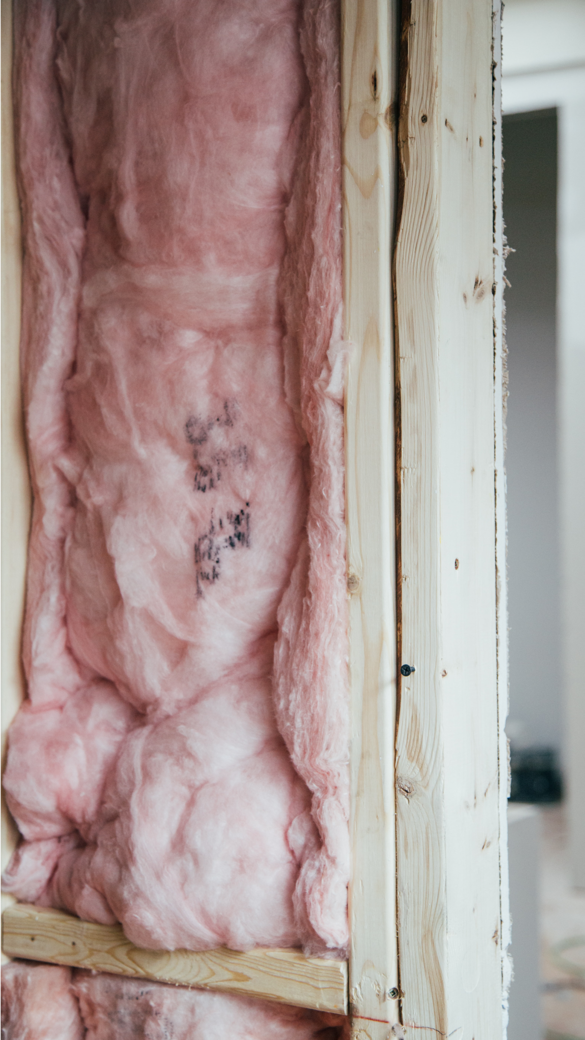 Une isolation en fibre de verre rose remplit une ossature murale en bois. Gros plan montrant la texture.