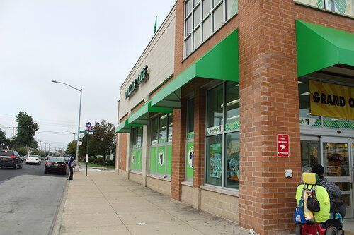 A store front with a green awning and a yellow sign that says grand opening.