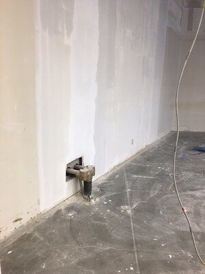 A room with a hole in the wall and a concrete floor.