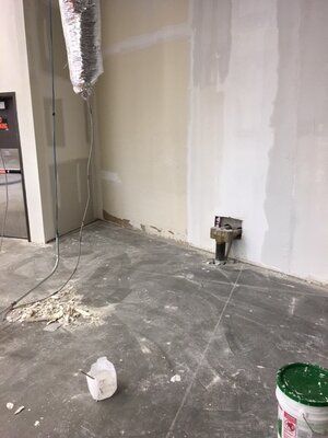 A room with a sink and a bucket of paint on the floor.
