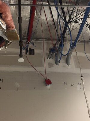 A person is working on a ceiling with a lot of wires hanging from it.
