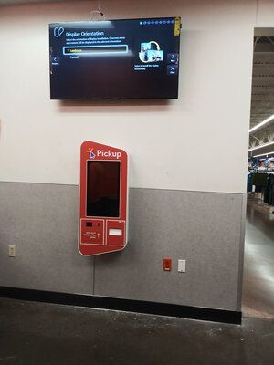 A pickup machine is hanging on a wall in a store.