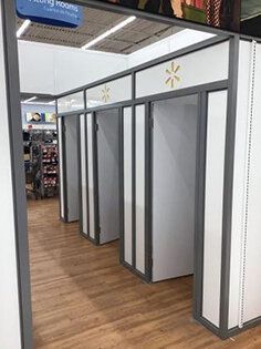 A row of changing rooms in a store with wooden floors.