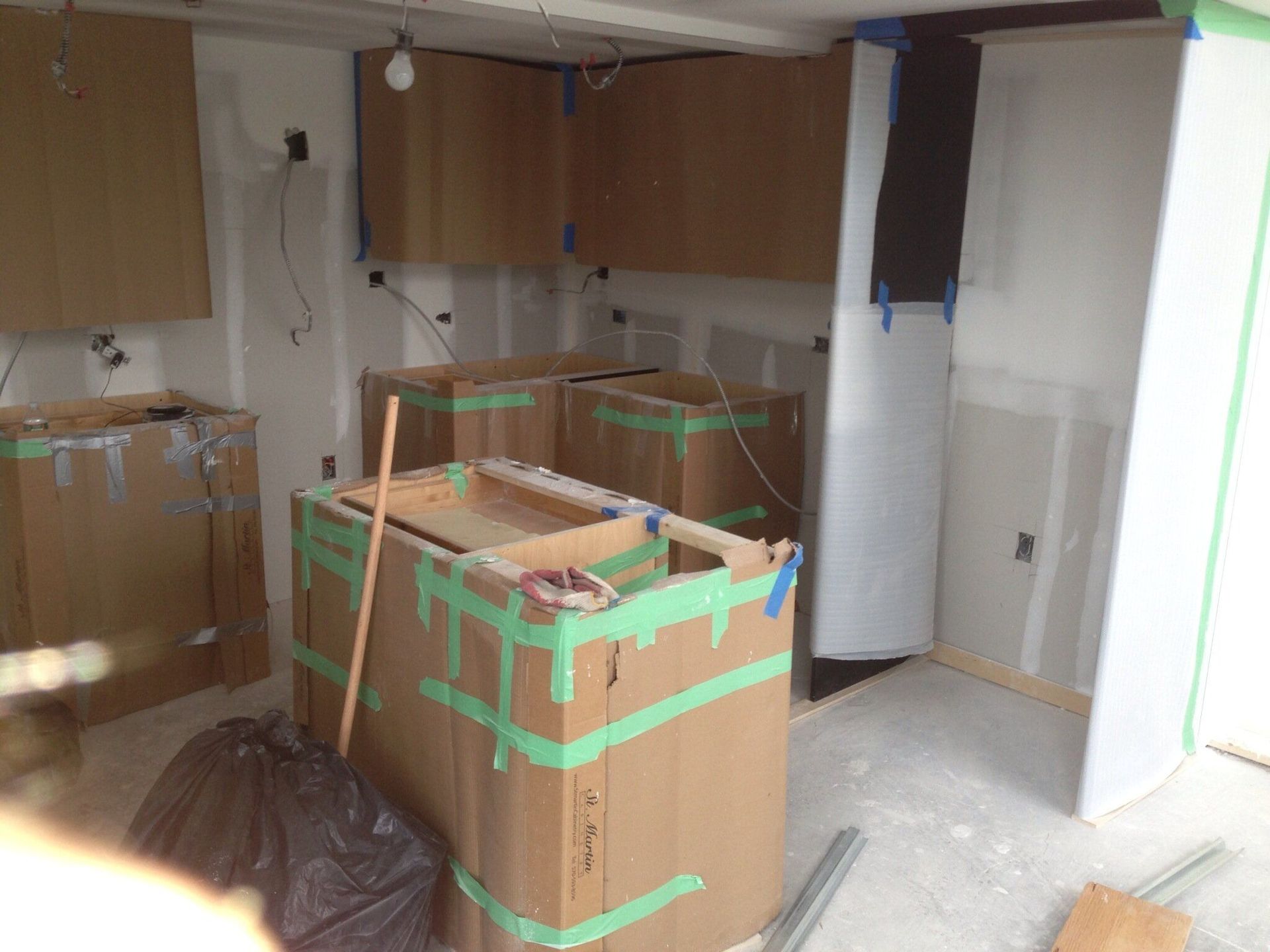 A kitchen under construction with cardboard boxes taped to the walls