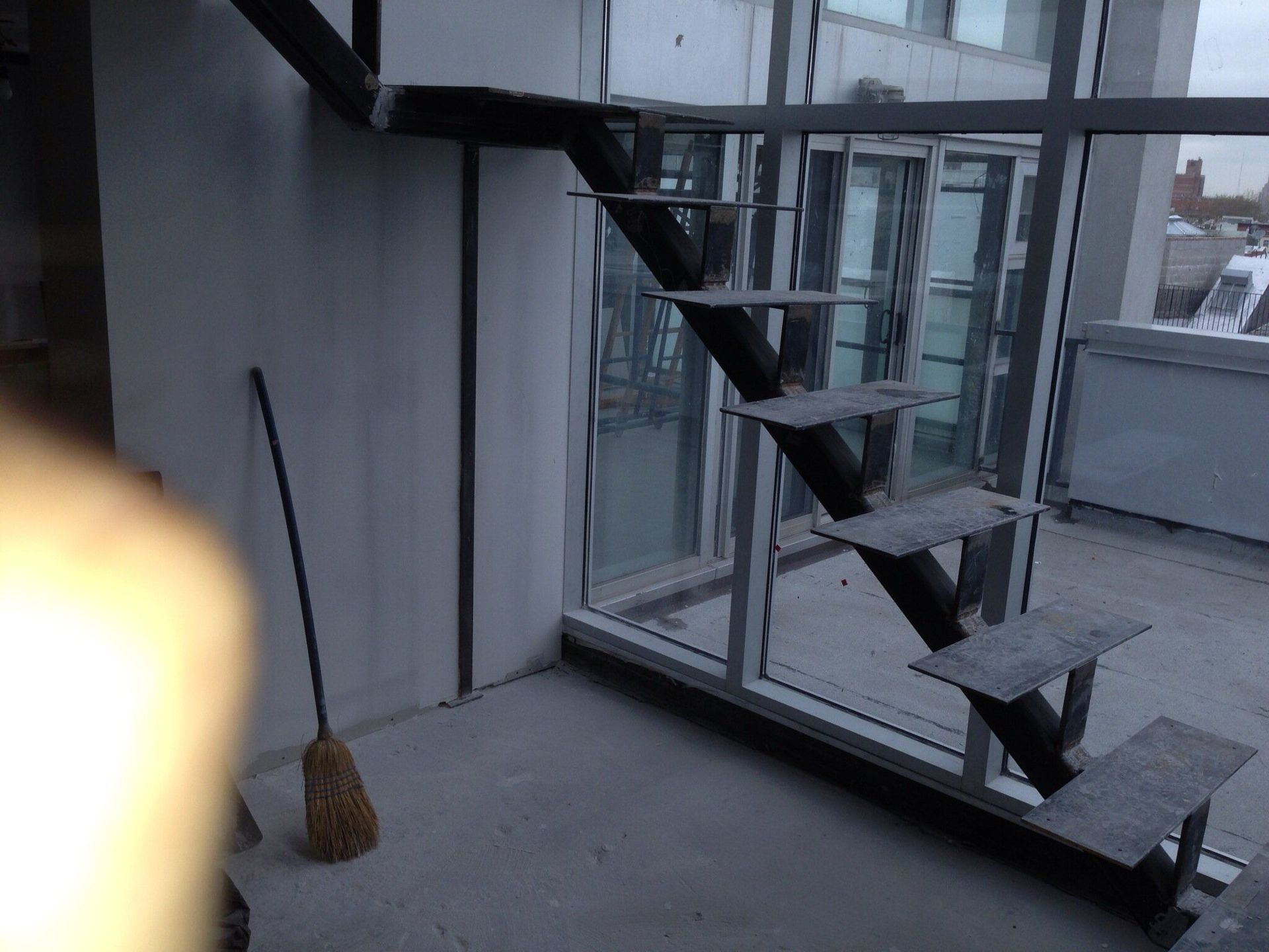 A broom is sitting on the floor next to a staircase.