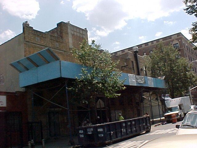 A blue dumpster is parked in front of a building