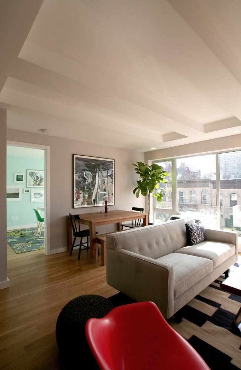 A living room with a white couch and a red chair