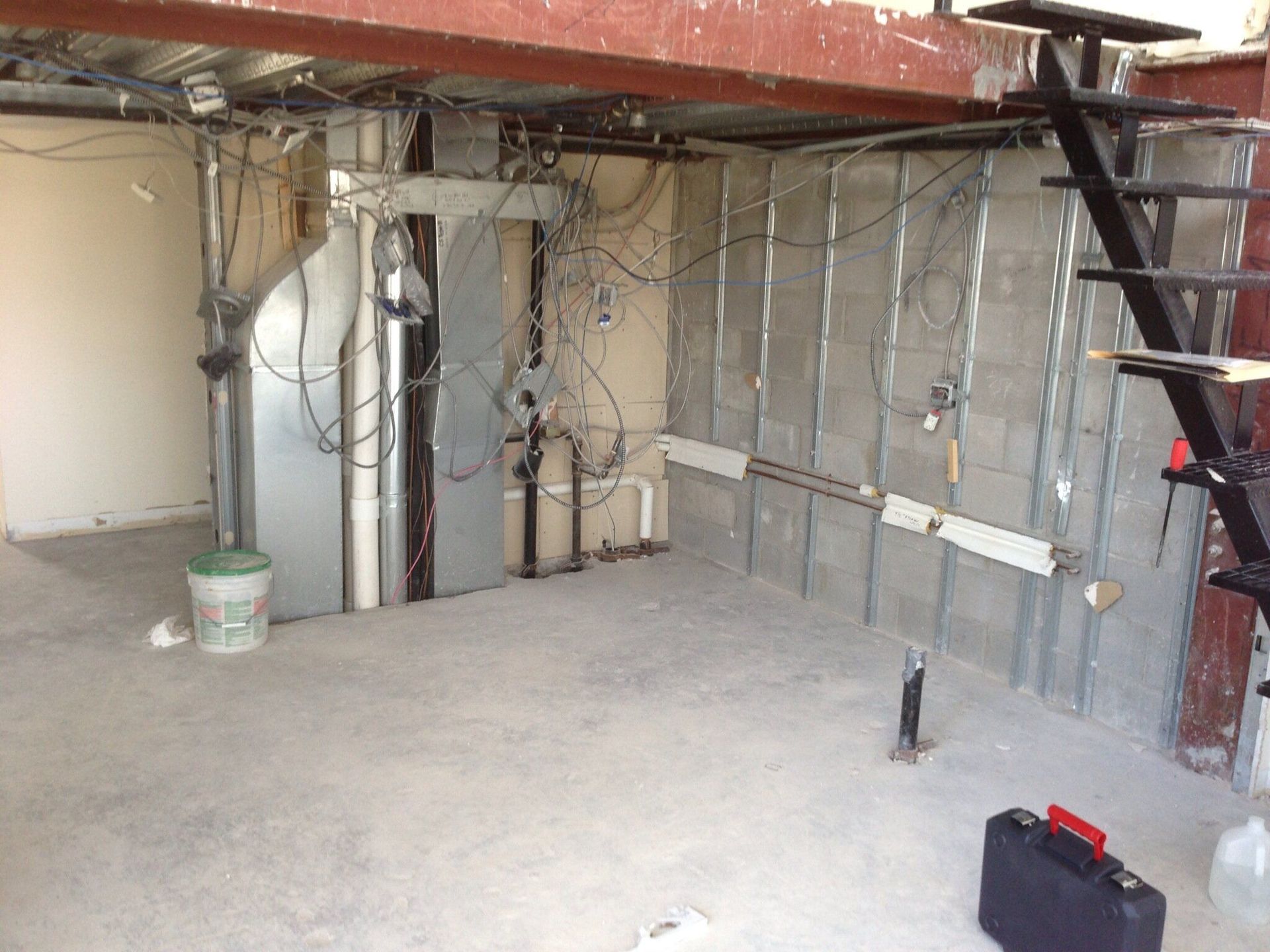 An empty basement with stairs and a briefcase on the floor