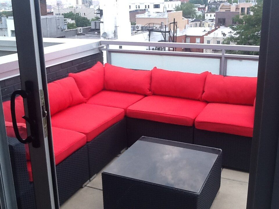A balcony with a couch and a table with red cushions