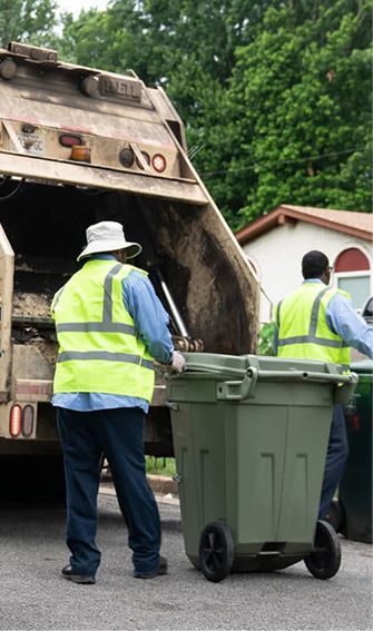 Two men are loading garbage into a garbage truck.