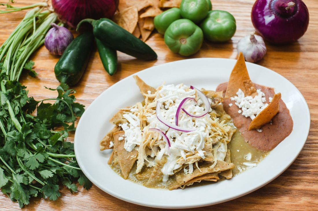 A white plate topped with a mexican dish on a wooden table.