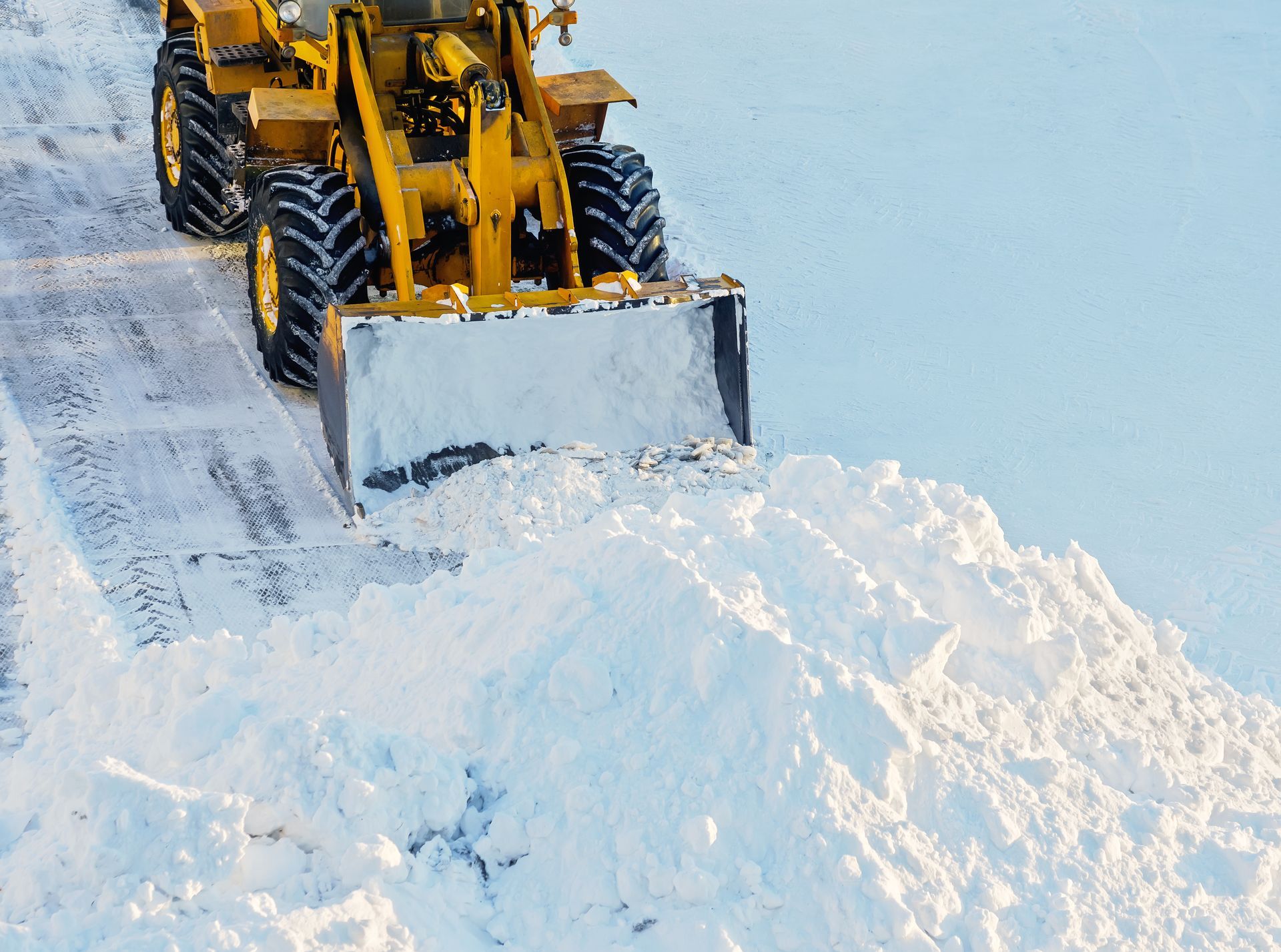 Une déneigeuse jaune dégage la neige d'une route.