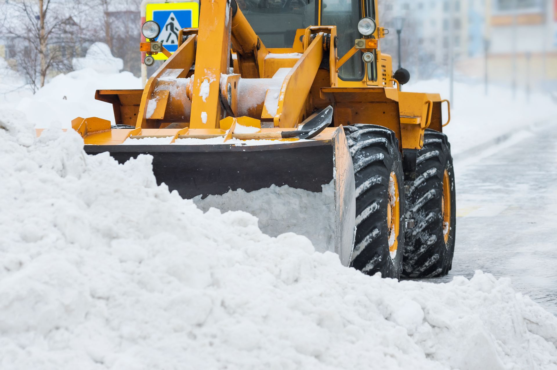 Une déneigeuse jaune dégage la neige d'une rue en hiver.