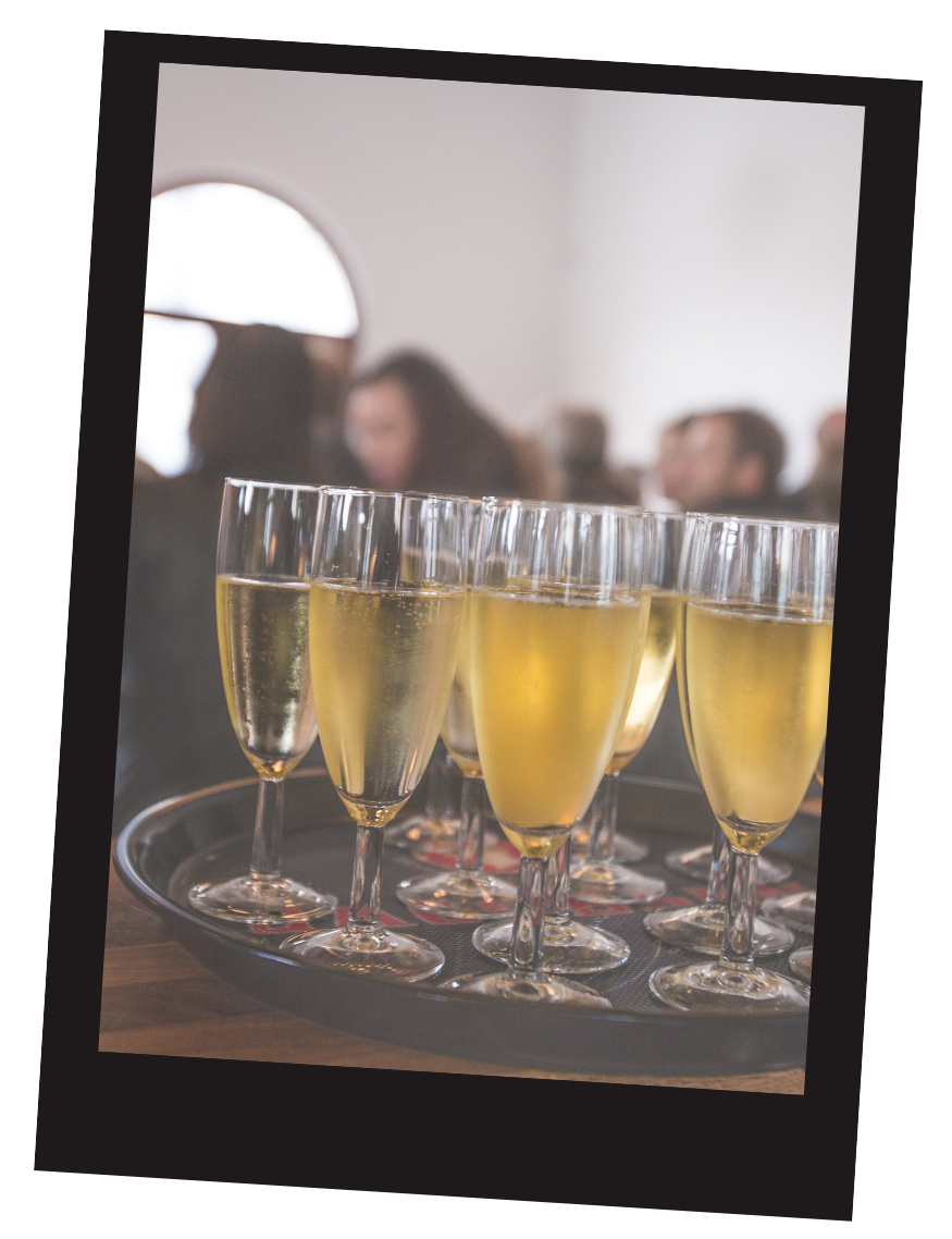 a tray of champagne glasses on a table with people in the background .