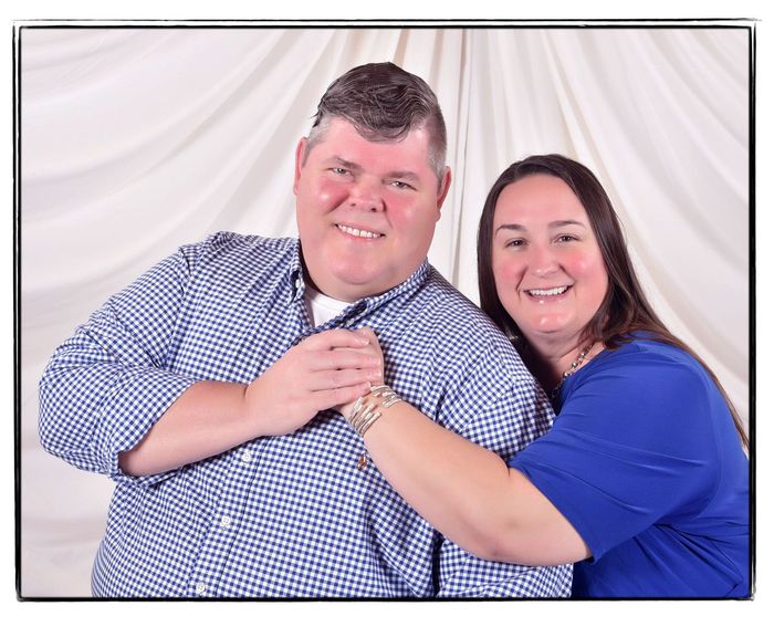 a man and a woman are posing for a picture and smiling for the camera .