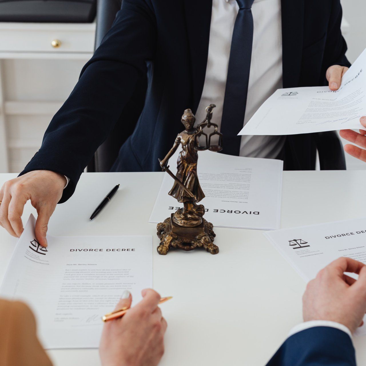 a group of people are sitting at a table with papers and a statue of lady justice